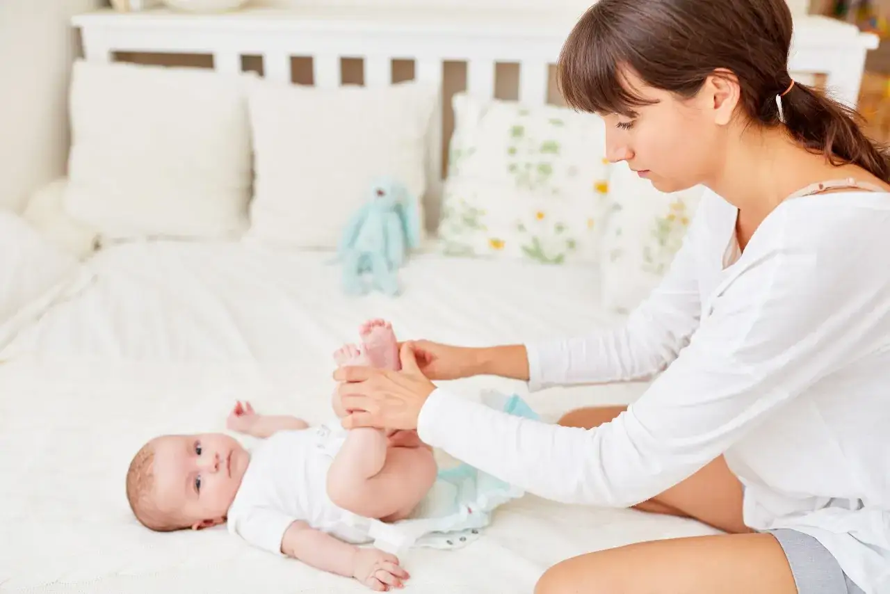 Mama zmienia pieluchę noworodkowi, zastanawiając się, jakie pieluchy dla noworodka będą najlepsze.